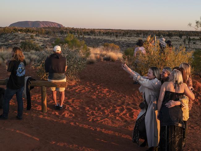 Tourists, including some dressed up for a night out taking a selfie, watch the sun set on Uluru, formerly known as Ayers Rock. Picture: Getty Images