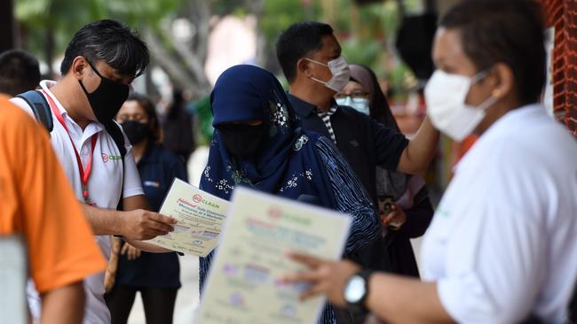 A woman, receives instructions from a social distancing ambassador at the Geylang Serai wet market in Singapore. Picture: AFP.