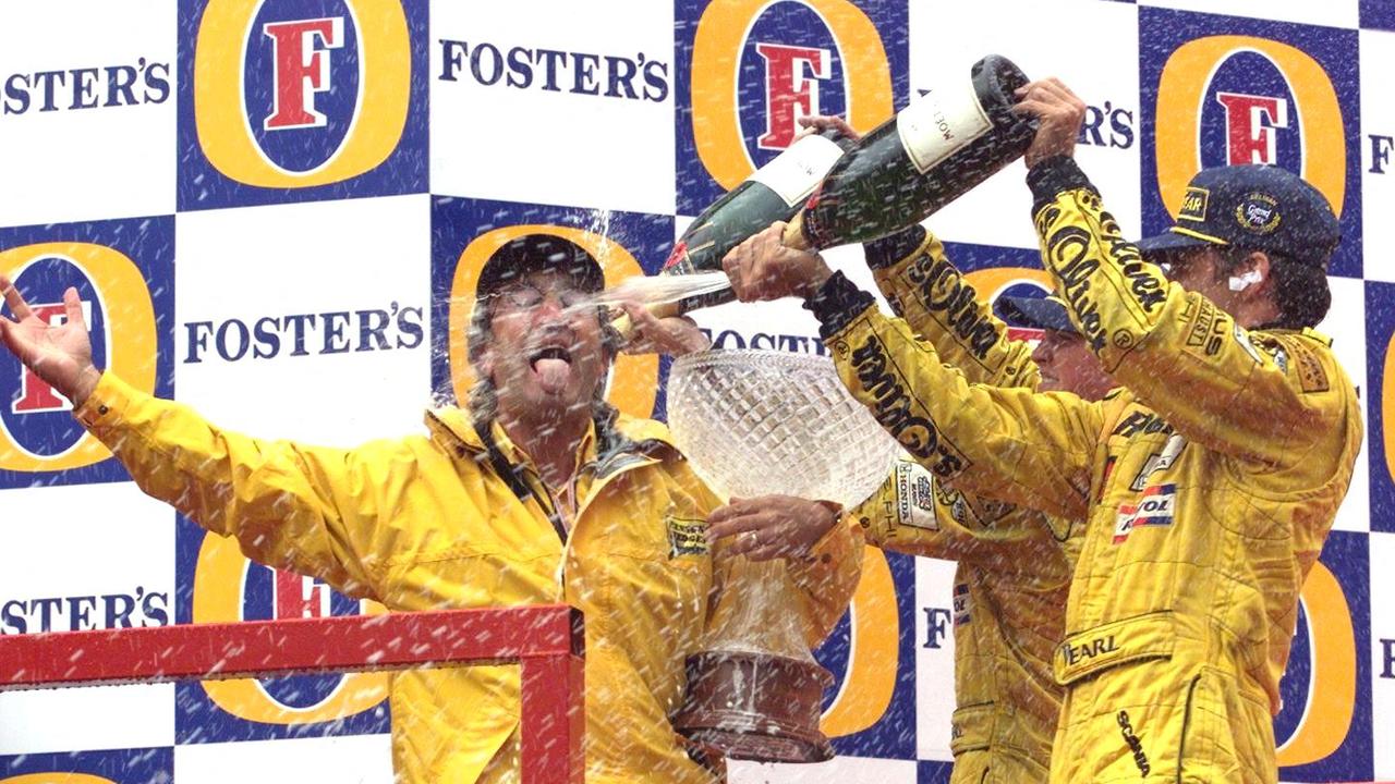 Damon Hill (R) and Ralf Schumacher (centre) spill champagne on their team director Eddie Jordan (L). Photo by ERIC CABANIS / AFP