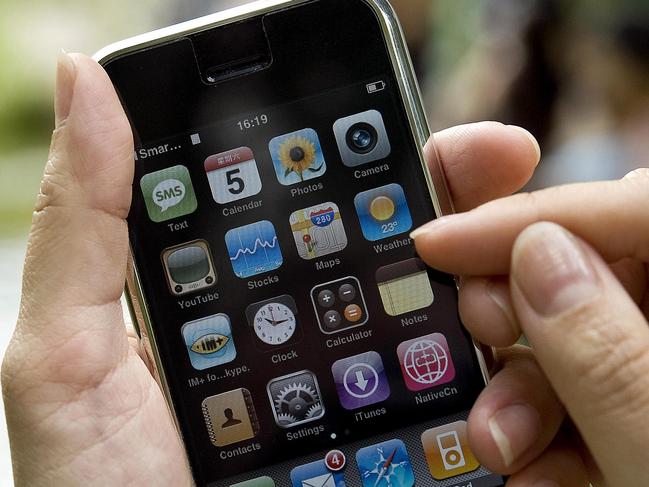 A woman holds up an iPhone handset along a street in Hong Kong on July 5, 2008. The updated and cheaper version of the iPhone is set to be released in cities from Tokyo to Sydney on July 11, 2008 but in Asia, where ownership of the latest brand is crucial social currency, the sleek original has already become the must-have accoutrement trendsetters. AFP PHOTO/Andrew ROSS