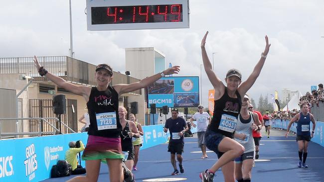 Gold Coast Marathon entrants Tina Kirwan, left, and Sara Wasson jump for joy crossing the finish line at last year’s event. Picture Mike Batterham