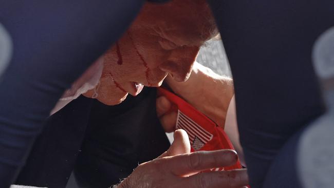 Secret Service agents tend to a stunned and bloodied former president Donald Trump on stage at a rally in Butler, Pennsylvania.