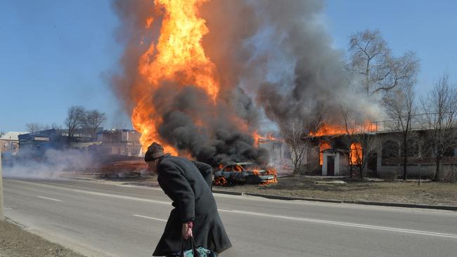 An elderly man walks as fire engulfs a gas station following an artillery attack on the 30th day of the Russian invasion of Ukraine in the northeastern city of Kharkiv. Picture: AFP