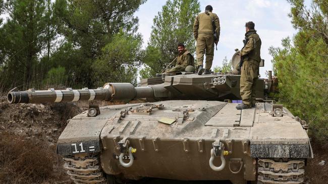 Israeli soldiers ride on a Merkava tank as it drives to an undisclosed location in northern Israel near the border with Lebanon. Picture: AFP