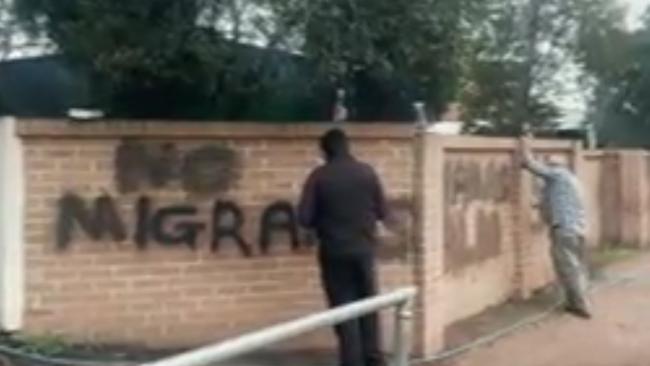 People scrub off the offensive graffiti from walls at the Australian Islamic College of Sydney on Friday morning. Picture: 7News