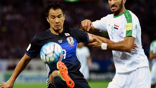 Japanese forward Shinji Okazaki (L) fights for the ball with Iraqi defender Ahmed Ibrahim (R).