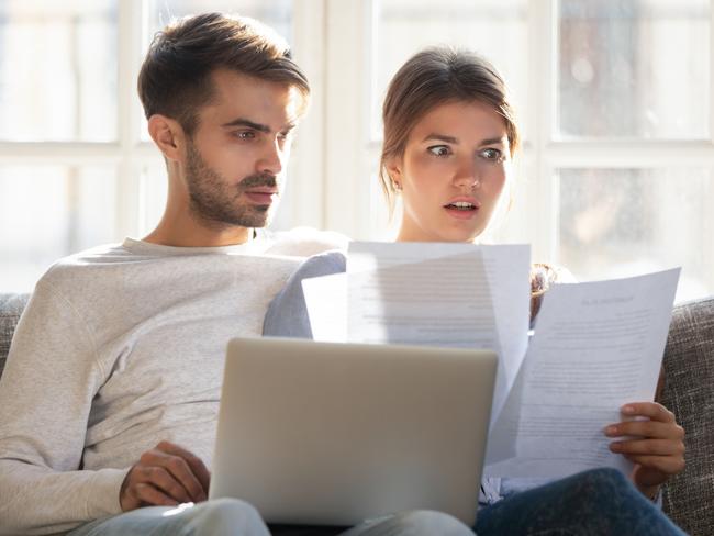 A couple sitting on the couch looking at their household bills including their energy costs. Picture: iStock.