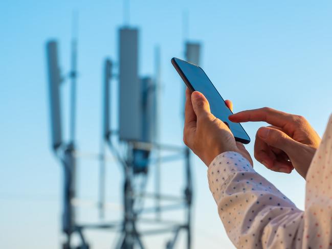 5G communications tower with man using mobile phone