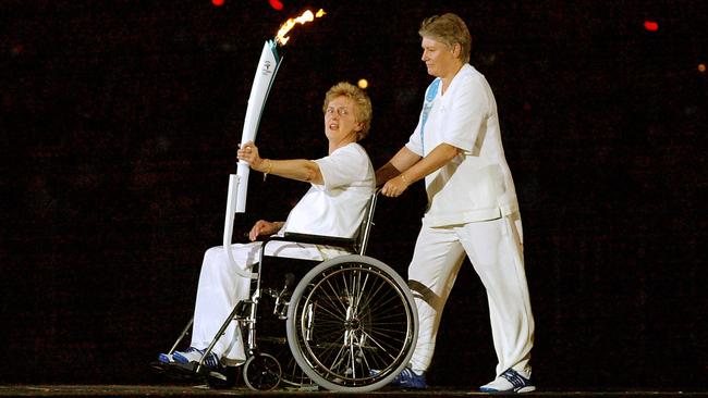 Olympic running legend Betty Cuthbert in wheelchair is escorted by Reelene Boyle as she holds the Olympic Relay torch during the opening ceremony of the Sydney Olympics in 2000.