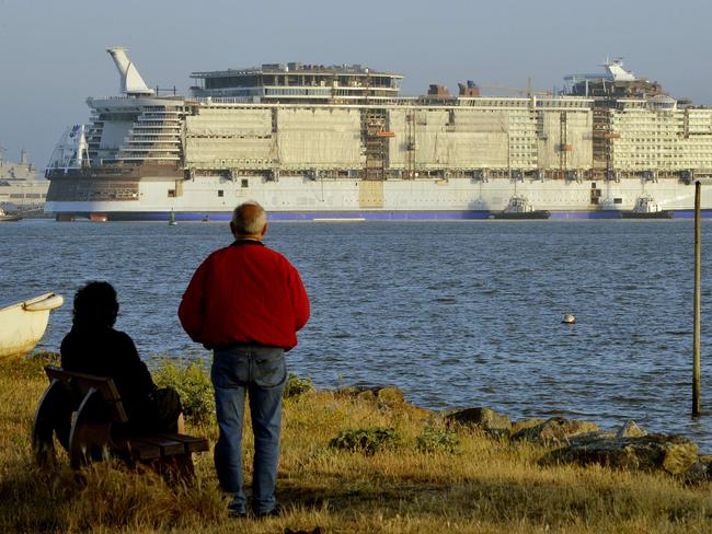 People watch from the shore as the cruise liner is towed.