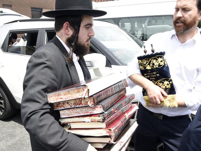 Synagogue members remove religious material from the damaged synagogue on Friday. Picture: Andrew Henshaw