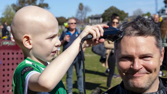 Riley Sinclair shaves East Bentleigh Soccer Club assistant senior coach Trent Thompson’s hair at the “Riley’s Kicking Goals” fundraiser.