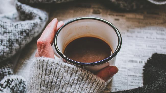 Woman wearing grey knit jumper holding hot drink