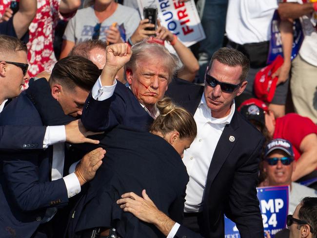 (FILES) Republican candidate Donald Trump is seen with blood on his face surrounded by secret service agents as he is taken off the stage at a campaign event at Butler Farm Show Inc. in Butler, Pennsylvania, July 13, 2024. A Florida judge appointed by Donald Trump has dismissed the criminal case against the former president on charges of mishandling top secret documents, on July 15, 2024 saying the way that Special Counsel Jack Smith was appointed was improper. (Photo by Rebecca DROKE / AFP)