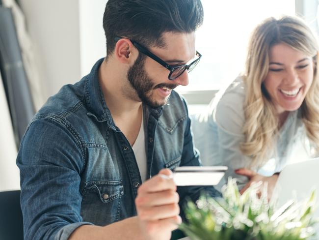 A happy young couple relaxing together and making some online purchases, money, relationships, generic