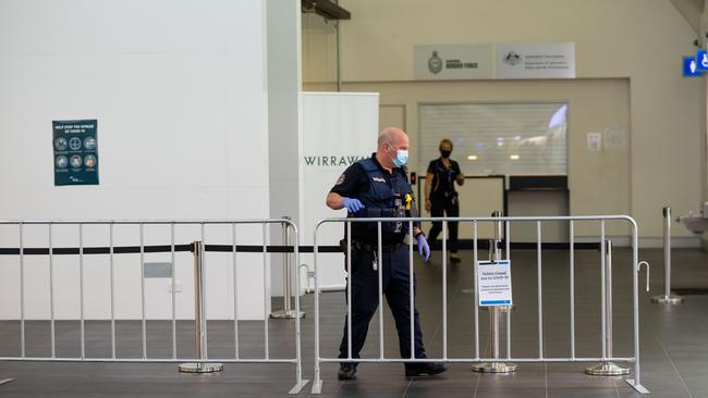 Two flights were arriving at Darwin International Airport from Adelaide today at 9.30am and 9.38am. Pictured are police awaiting the arrival of passengers for transfer to Howard Springs. Picture: Che Chorley