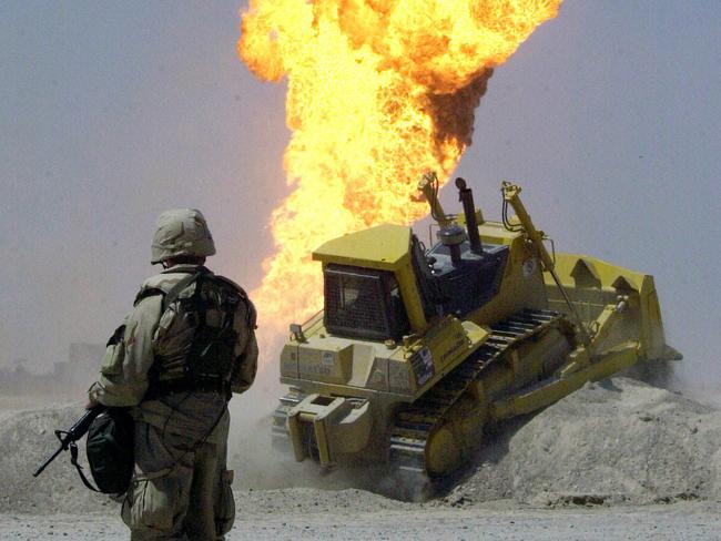 A US Army soldier stands guard duty near a burning oil well in the Ramaila Oil Fields in Southern Iraq 02 Apr 2003. Coalition forces have secured the southern oil fields and are in the process of extinguishing the burning wells that were set ablaze in the early stages of Operation Iraqi Freedom. ((RELEASED) War on Iraq - Military Operation Iraqi Freedom by USA led coalition armed forces. /Iraq/War