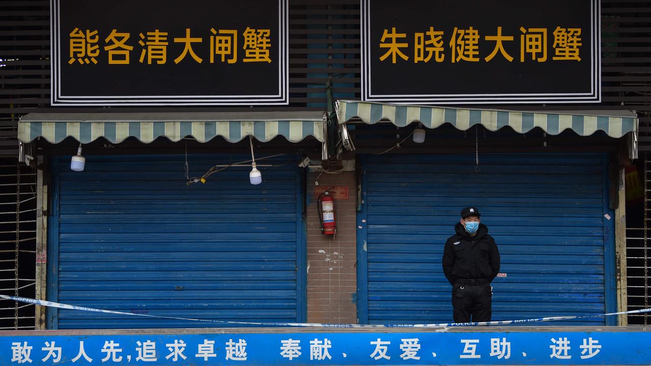 A security guard stands outside the Huanan Seafood Wholesale Market in January 2020. Picture: Hector RETAMAL / AFP.