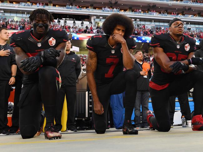 (FILES) In this file photo taken on October 6, 2016  (L-R) Eli Harold #58, Colin Kaepernick #7, and Eric Reid #35 of the San Francisco 49ers kneel in protest during the national anthem prior to their NFL game against the Arizona Cardinals at Levi's Stadium  in Santa Clara, California.   National Football League owners reached agreement May 23, 2018 on a policy which would require players to stand during the national anthem but give them the option of remaining in the locker room if they preferred.The issue of how to handle player protests has loomed over the NFL's owners meeting in Atlanta, with the sport anxious to avoid a repeat of the controversy which divided the league last season.The kneeling protest was started by former San Francisco 49ers quarterback Colin Kaepernick in 2016 as a way to protest police brutality, racial injustice and social inequality. Kaepernick's protest followed a wave of deaths involving black men during confrontations with law enforcement.   / AFP PHOTO / GETTY IMAGES NORTH AMERICA / Thearon W. Henderson