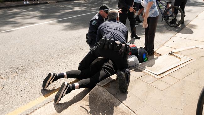 Police hold down a motorcyclist that collided with a cyclist at the SANTOS Tour Down Under in Tea Tree Gully on Thursday, January 18, 2023. (The Advertiser/ Morgan Sette)