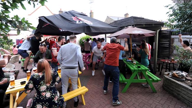 Brentford FC fans celebrate a goal in a pub garden next to the stadium at Griffin Park