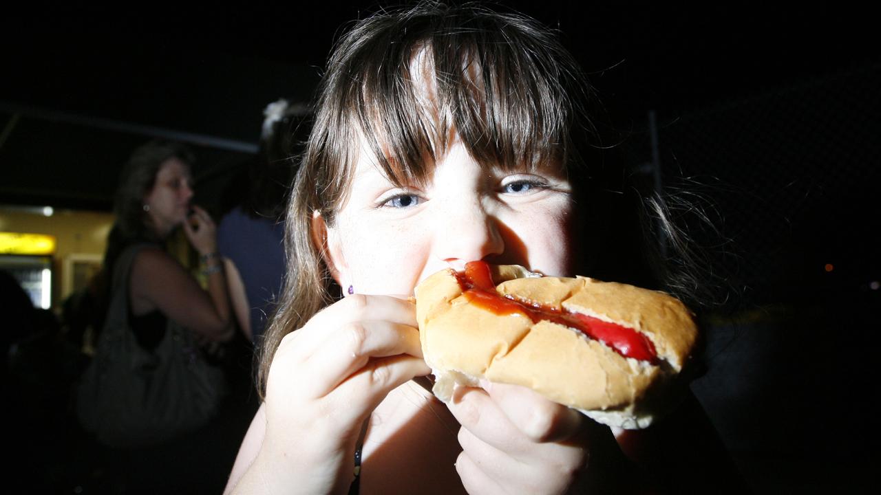 2011: Indya Smith tucks into a hot dog at the New Year's Eve celebrations at North Ipswich Reserve. Photo: Claudia Baxter