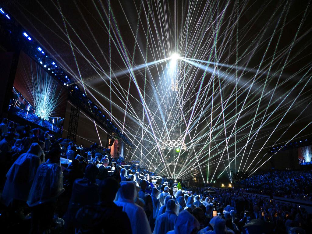 Spectators watch the the Eiffel Tower as lasers light up the sky during the opening ceremony of the Paris 2024 Olympic Games in Paris on July 26, 2024. (Photo by Oli SCARFF / AFP)