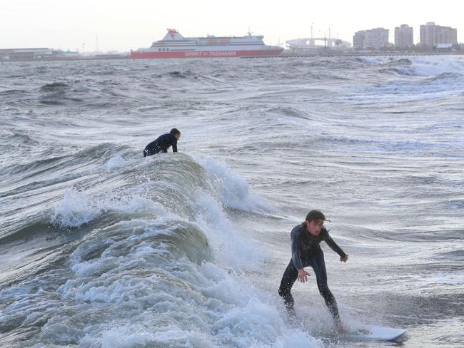 A surfer catches a wave in Port Phillip Bay in Port Melbourne. AAP Image/David Crosling