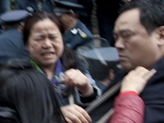 In this March 19, 2015 photo, security guards scuffle with protestors angry about failed investments with Hunan Bofeng Asset Management Ltd. outside of a branch of the Industrial and Commercial Bank of China in Changsha in southern China's Hunan province. Thousands of Chinese savers who entrusted money to an informal finance industry that operates with little government oversight are suffering painful losses as borrowers default and real estate and other ventures fail. (Chinatopix Via AP) CHINA OUT