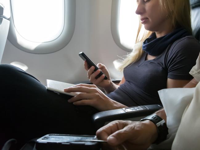 Casual Clothing Woman in Plane Seat Browsing Her Smart Phone and Holding Documents for Immigration Formalities Hand of Man on Foreground Focus on Female Hands