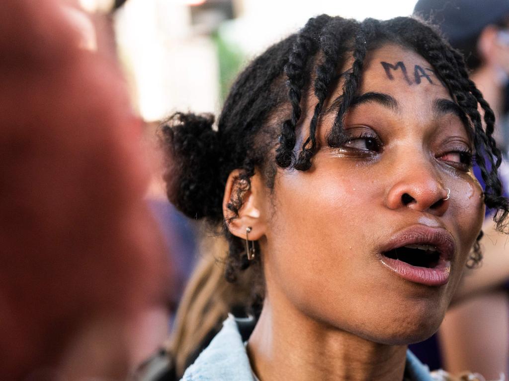 A woman cries as she is overcome by emotion after berating a line of policemen through a metal fence recently erected in front of the White House. Picture: Roberto Schmidt