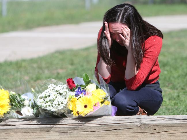 A woman lays flowers at a Caltex services station in Queanbeyan, where a man was fatality stabbed. Picture Kym Smith