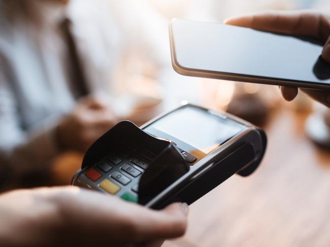 Example of digital wallet payment system in cafe: closeup of male customer swiping his smartphone over terminal paying with his credit card via phone