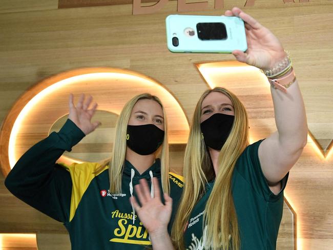 Australian softball players Shannon Keevers (L) and Ellen Roberts wave while on a video chat as they prepare to leave for the Tokyo Olympics, at Sydney International Airport on May 31, 2021. (Photo by SAEED KHAN / AFP)