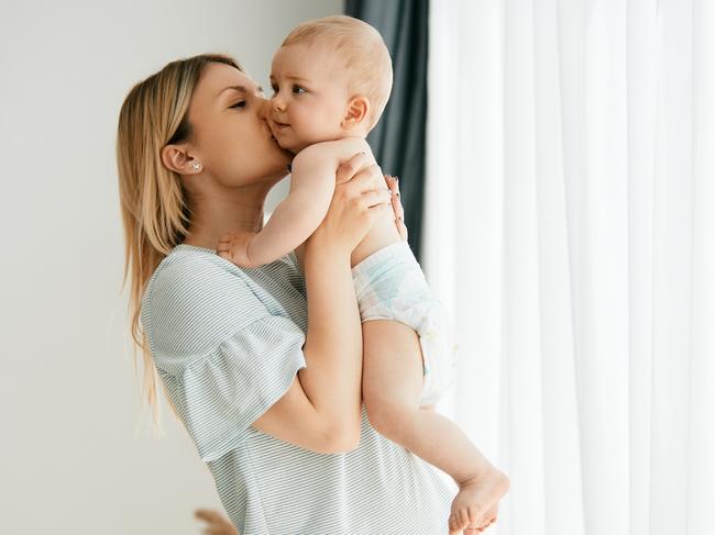 Young affectionate mother holding her baby boy and kissing him at home. Copy space. istock image