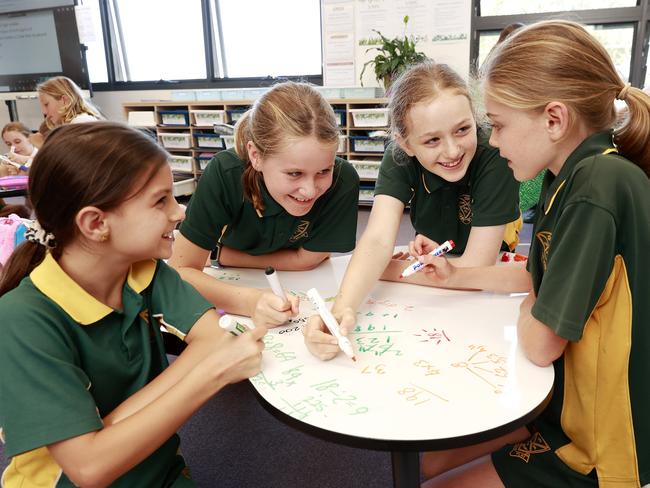 DAILY TELEGRAPH. FEBRUARY 15, 2023.Pictured at Curl Curl North Public School today are students (L-R) Keira Stephens 10, Rosie Lawry 10, Matisse Hayes Black 11 and Carmen Schreiber 10, sitting on the floor and using the white board desks to do their work on. Picture: Tim Hunter.