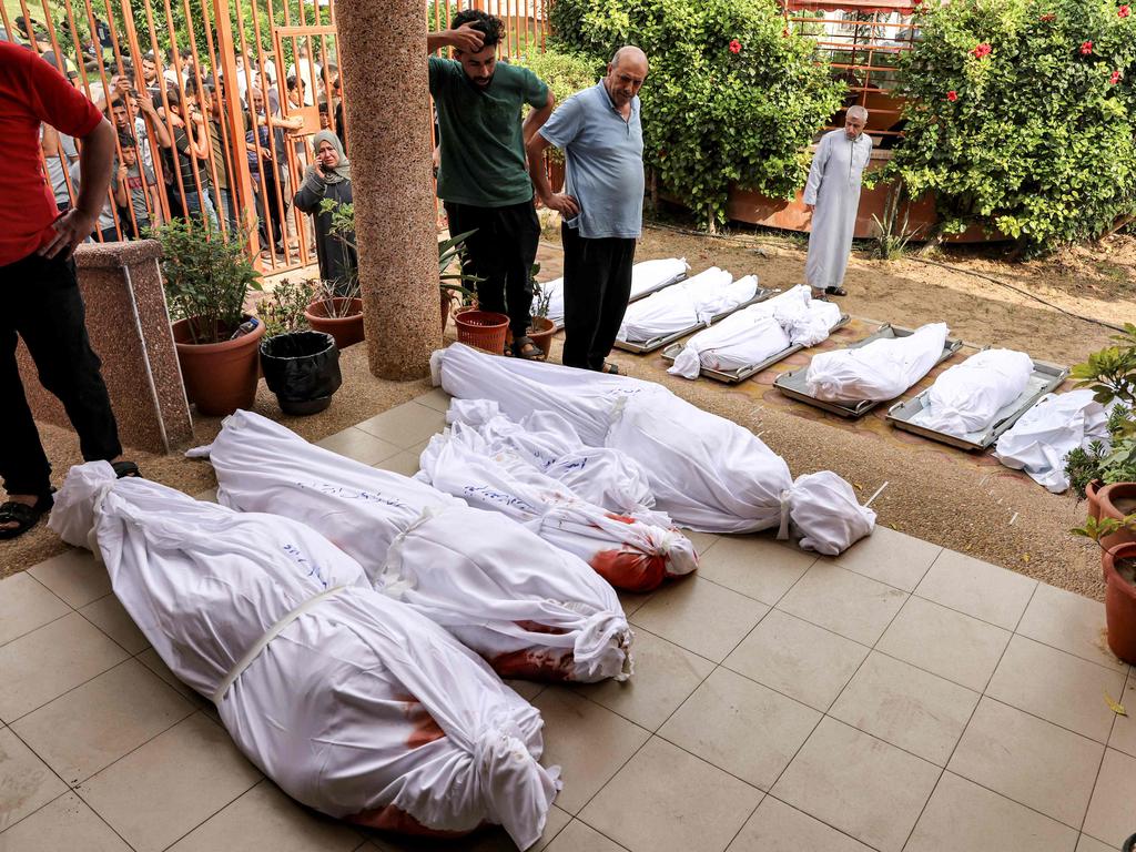 People gather in the courtyard of a morgue by the wrapped bodies of Palestinians killed in an Israeli air strike in Khan Yunis in the southern Gaza Strip. Picture: AFP