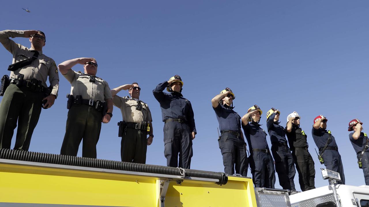 Law enforcement and fire personnel salute from an overpass as a motorcade with the body of Ventura County Sheriff's Sgt. Ron Helus passes by. Picture: AP