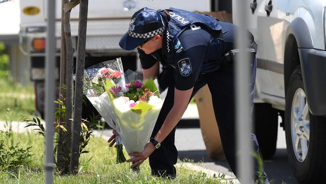 A Police officer places flowers brought over by a neighbour outside the home. Picture: AAP/Dan Peled