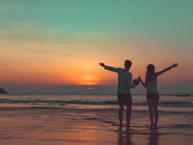 ESCAPE:  Couple drinking cocnut juice while watching the sunset over the ocean in Bali, Indonesia. Picture: Istock