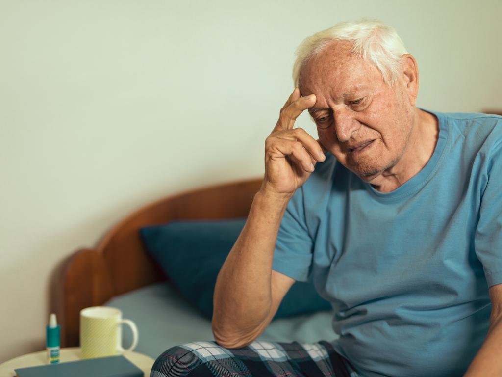 Senior Man Sitting On Bed At Home Suffering From Depression