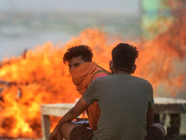 Family members sit next to a burning pyre at a cremation ground amid the coronavirus pandemic in India. Picture: AFP