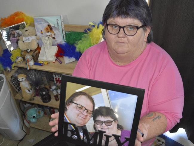 Toowoomba woman Jo Coyne has been battling against the National Disability Insurance Scheme for months over her plan. She’s pictured holding a photo of her son Thomas, who tragically died.