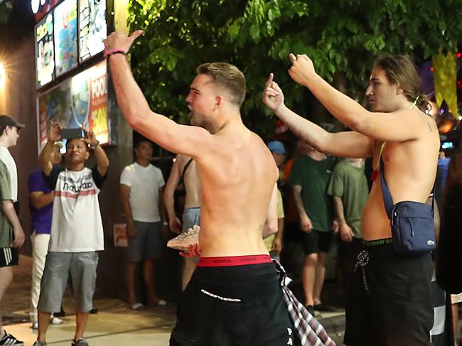 Two shirtless Australians give the finger to another group of young Aussies. Picture: Liam Kidston