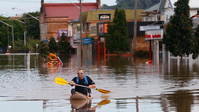 A man paddles a kayak down a Lismore street yesterday.