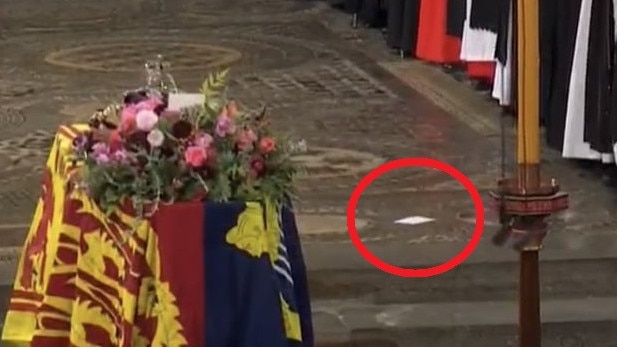 The errant piece of paper beside the Queen's coffin.