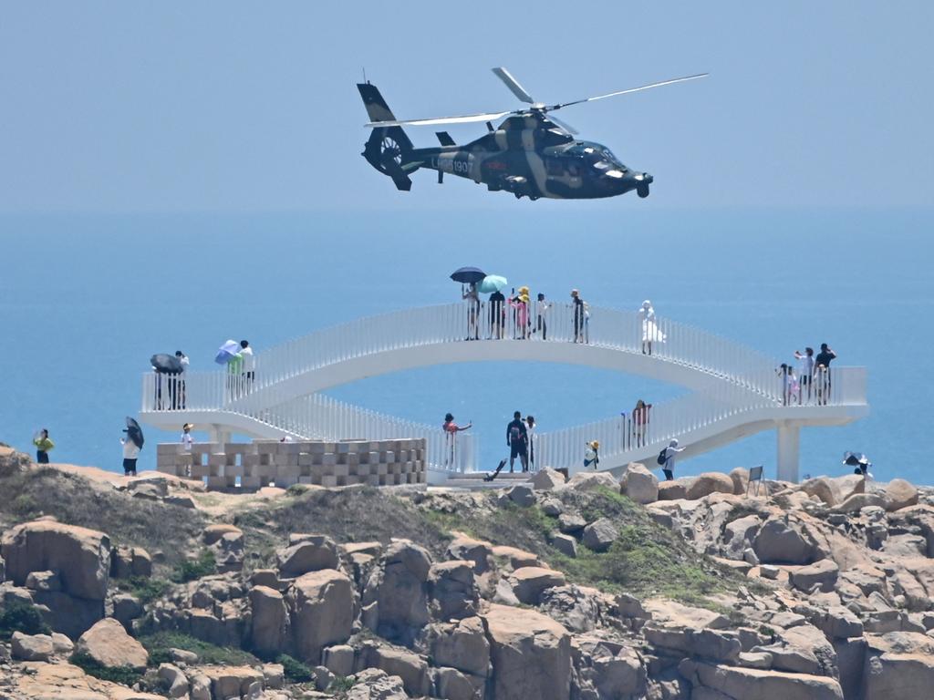 Tourists look on as a Chinese military helicopter flies past Pingtan island, one of mainland China's closest point from Taiwan. Picture: AFP