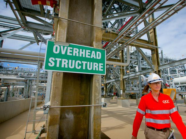 A worker walks past a sign reading "Overhead Structure" at the Queensland Curtis Liquefied Natural Gas (QCLNG) project site, operated by QGC Pty, a unit of Royal Dutch Shell Plc, in Gladstone, Australia, on Wednesday, June 15, 2016. Gas from more than 2,500 wells travels hundreds of miles by pipeline to the project, where it's chilled and pumped into 10-story-high tanks before being loaded onto massive ships. Photographer: Patrick Hamilton/Bloomberg