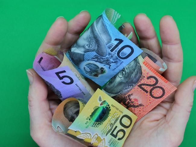 POV (point of view) of a person holding Australian dollar currency bank notes with his two hands isolated on a green background. ; share dividends generic