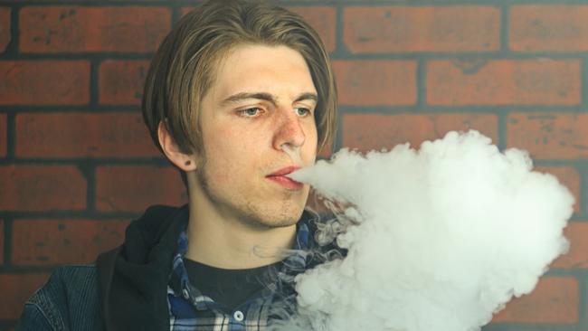 Vape teenager. Portrait of young handsome guy smoking an electronic cigarette in the bar. Bad habit that is harmful to health. Vaping activity. Picture: iStock / Aleksandr Yu